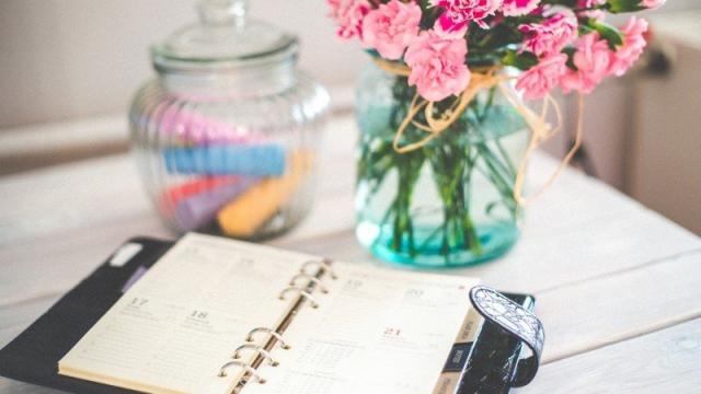 Personal Organizer And Bunch Of Pink Flowers In Vase On Desk